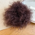 Detailed view of dark brown curly faux hair scrunchie for messy bun styling on wood table - Brown