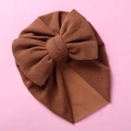 Detailed close-up of brown newborn turban hat with double bow knot on pink background - Coffee