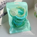 Detail of spiral hair ties set in green shades inside a semi-transparent zip pouch - 8# Green Series