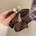 Bruine kant haarelastiek met twee grote imitatieparels vastgehouden voor een effen wand - #1 Donkerbruine Scrunchie