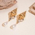 Golden shell earrings with white drop pearls and crystal accents on a sandy background - Gold