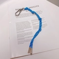 Détail d'un porte-clés en corde tressée bleue avec fermoir argenté sur un livre - 11.A05 Lanière Bleu Foncé
