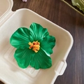 Detail view of a green acrylic hibiscus flower hair clip with yellow pistil texture - Green