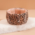 Detailed view of leopard print acrylic bracelet sections on a white natural stone pedestal - Pink