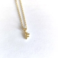 Detailed macro view of minimalist gold letter F pendant necklace on white surface - Letter F