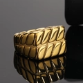 Macro di anello industriale dorato con trama a venature su una piattaforma a specchio nera - US 7 / Oro
