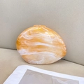 Detailed macro view of amber stone pattern on smooth acrylic pebble evening clutch bag - Apricot