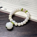 White Bodhi seed bracelet with cat paw carving and green accents on vintage book - White Jade Bodhi + Lotus