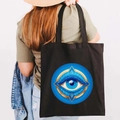 Black canvas tote bag featuring a blue and gold Greek Evil Eye graffiti print - Design U-Refined Round Eye-Black