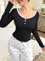 Dettaglio dello scollo a V con pizzo e bottoni decorativi su un top pigiama a costine - S / Nero