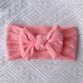 Detail of pink knitted baby headband with large bow and soft ribbed texture on fabric - Pink