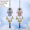 Hamsa Hand wind chime with Evil Eye beads, gold bells, and blue tassels hanging in blue sky - Hamsa Hand Gold Bells (NO.7)