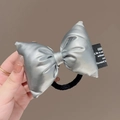 Primer plano de un lazo para el pelo de tela plateada con goma negra y etiqueta de texto - Coletero / Plata (D-4347-3)