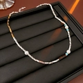 Detail of necklace with silver beads, pearls, and tiger eye stone on black display - Silver Coffee