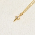 Collana a stella dorata con ciondolo in zirconia trasparente su sfondo beige testurizzato - Stella a Quattro Punte Zirconia