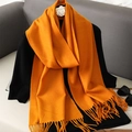 Detail shot of the soft orange scarf texture with classic tassel fringe on a gray background - Bright Orange