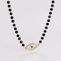 Detailansicht der Perlenkette mit goldenem Evil-Eye-Anhänger und funkelnden Strasssteinen - Schwarz
