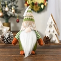 Close-up of a festive Christmas gnome featuring a green knitted hat and white faux fur beard - Striped Hat Style