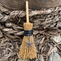 Detail of a mini wooden witch broom with a silver starfish charm and fiber bristles - Straw Broom + Starfish
