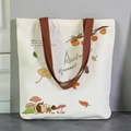 Beige canvas tote bag with Autumn Harvest hedgehog print and brown woven handles - Autumn Leaves