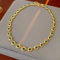 Detail of vintage gold necklace with green stones on grey velvet jewelry box - Necklace-Gold-Green