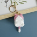 Pink and white handmade crochet cat keychain with golden metal clasp on blue background - Pink and White Cat