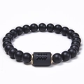Detailed macro view of matte black onyx Aquarius zodiac bead bracelet with gold spacers - Aquarius