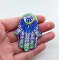Handheld view of multi-color Hamsa Hand acrylic pendant with Evil Eye charm - Style 22