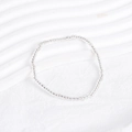 Macro shot of clear minimalist beaded bracelet on white textured fabric background - Clear