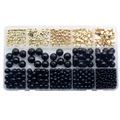Macro detail of DIY jewelry set with gold star beads and black pearls in a plastic box - Black