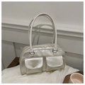 Detail view of a white PU leather handbag with dual front pockets and glossy pearl finish - Pearl White