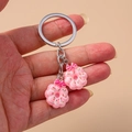 Détail d'un porte-clés donut rose avec vermicelles colorés et un petit nœud rose - Décoration de nœud / Fleur Rose
