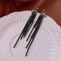 Close-up of black star-shaped earrings with long tassel chains on a white plate - Black Star Tassel (32#)