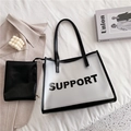 Transparent PVC tote bag with black support text and inner leather pouch on bed - White