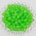 Close-up of grass green round glass beads in a clear tray for DIY jewelry making - 4mm / Apple Green