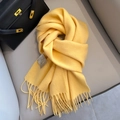 Soft yellow wool scarf with fringe detail folded elegantly on a stylish leather chair - Yellow