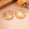 Détail des boucles d'oreilles dorées torsadées en U avec texture sur fond vintage chic - Boucle Texturée en Diamant (WGXA035055011B)