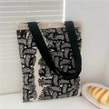 Detail of flower knit tote bag with black handles and magnetic snap closure on beige fabric - Knit Texture