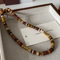 Beaded necklace with natural agate stones in earth tones and gold spacers on a wood tray - Egg Yolk Stone Necklace XL0326