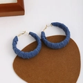 Detail shot of vintage denim-wrapped hoop earrings on a minimalist brown base cloth - Blue