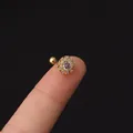 Golden flower helix piercing with cubic zirconia inlay held by hand for scale - Sun Flower (347-7#G)