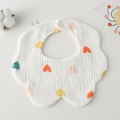 Detail of petal-shaped cotton gauze baby bib with colorful heart print and snap button - Gauze Flower Scarf - White Background With Peach Hearts