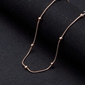 Roségoldene Edelstahl-Schlangenkette mit Perlen auf strukturiertem schwarzem Hintergrund - 1.2mm*50cm / Roségold