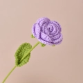Handmade crochet purple rose with green stem and leaf on a soft pink background - Light Purple Rose