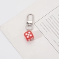 Detail of creative red dice keychain with silver lobster clasp on a white paper background - Red Dice