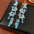 Detail von silbernen Quastenohrringen mit hellblauen Schmetterlingen und glänzenden Strass - Silbernadel-Blau
