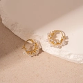 Macro view of gold-plated C-shaped earrings with pearls and zircon stones on stone base - Floral Geometric Ear Buckle / Gold