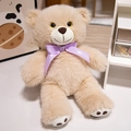 Hellbrauner Teddybär aus Plüsch mit violetter gepunkteter Schleife in gemütlichem Heim - Hellbraun / 25cm