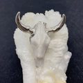 Macro detail of white acrylic bull skull pendant with silver horns on a crystal base - No.12 Carved White with Silver Horns