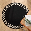 Modern black geometric round rug with a checkered border on fishbone wood flooring - Checkered